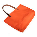 Flame orange waxed canvas tote with brown leather handles