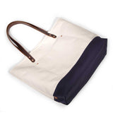 Natural canvas tote with navy bottom and brown leather handles