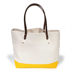 Natural canvas tote with yellow bottom and brown leather handles