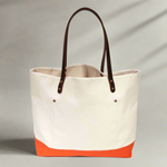 Lifestyle Natural canvas tote with orange bottom and dark brown leather handles