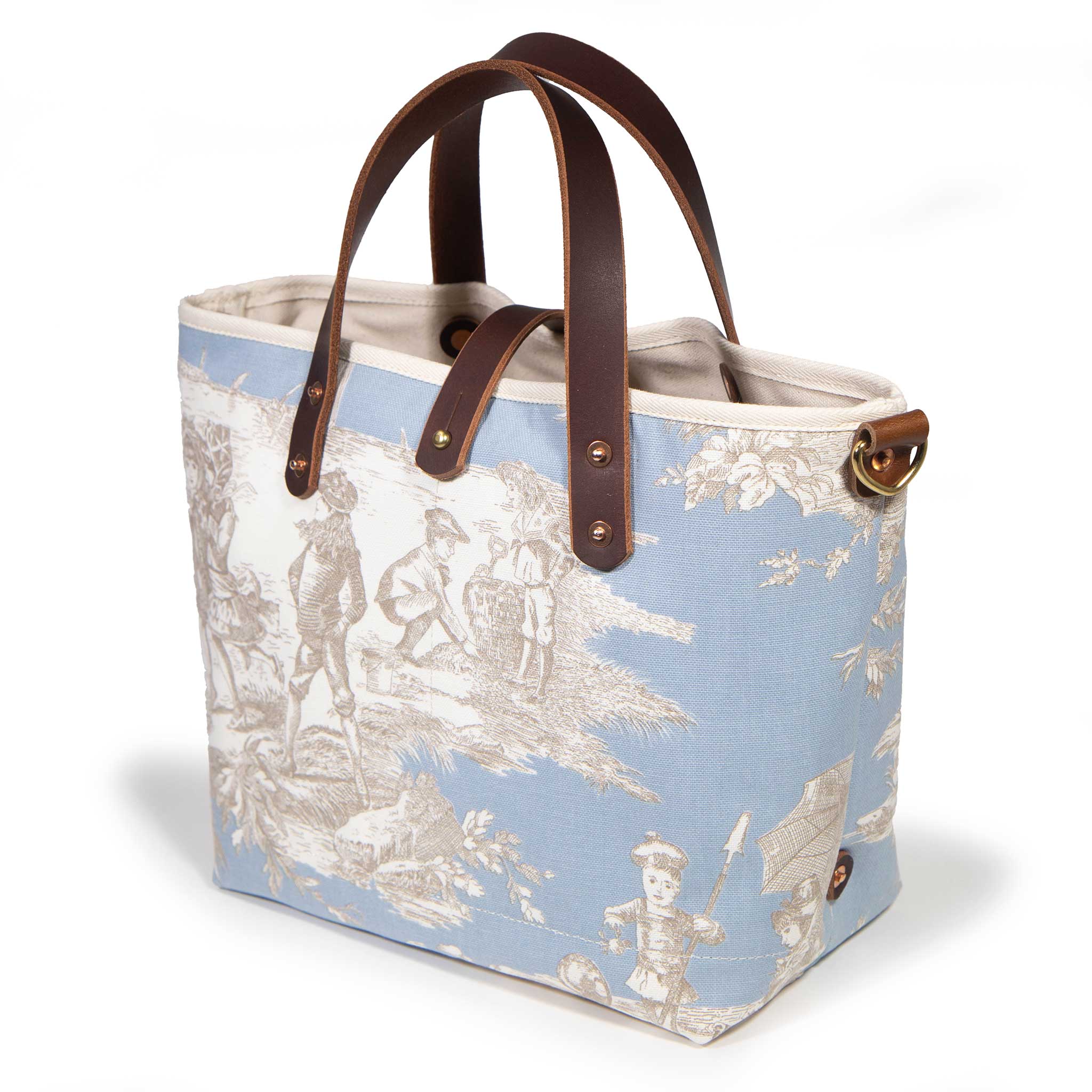 Seaside Toile Mini Tote in powder blue, three-quarter view, with mahogany leather handles and a brass D-ring