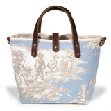 Front of the powder blue Seaside Toile Mini Tote, children at play along the shore, with mahogany handles and button tab