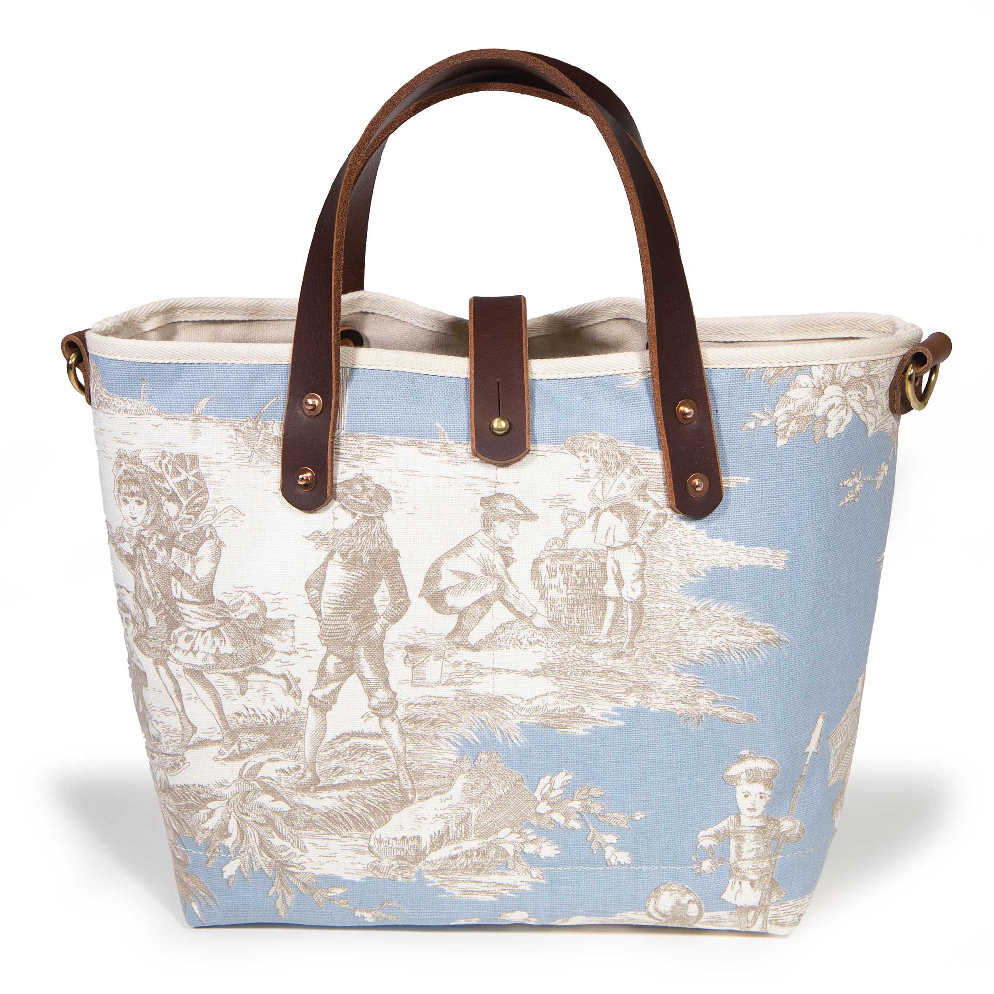 Front of the powder blue Seaside Toile Mini Tote, children at play along the shore, with mahogany handles and button tab
