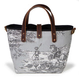 Front of the fog grey Seaside Toile Mini Tote, children wading with nets along the shore, with mahogany handles and button tab