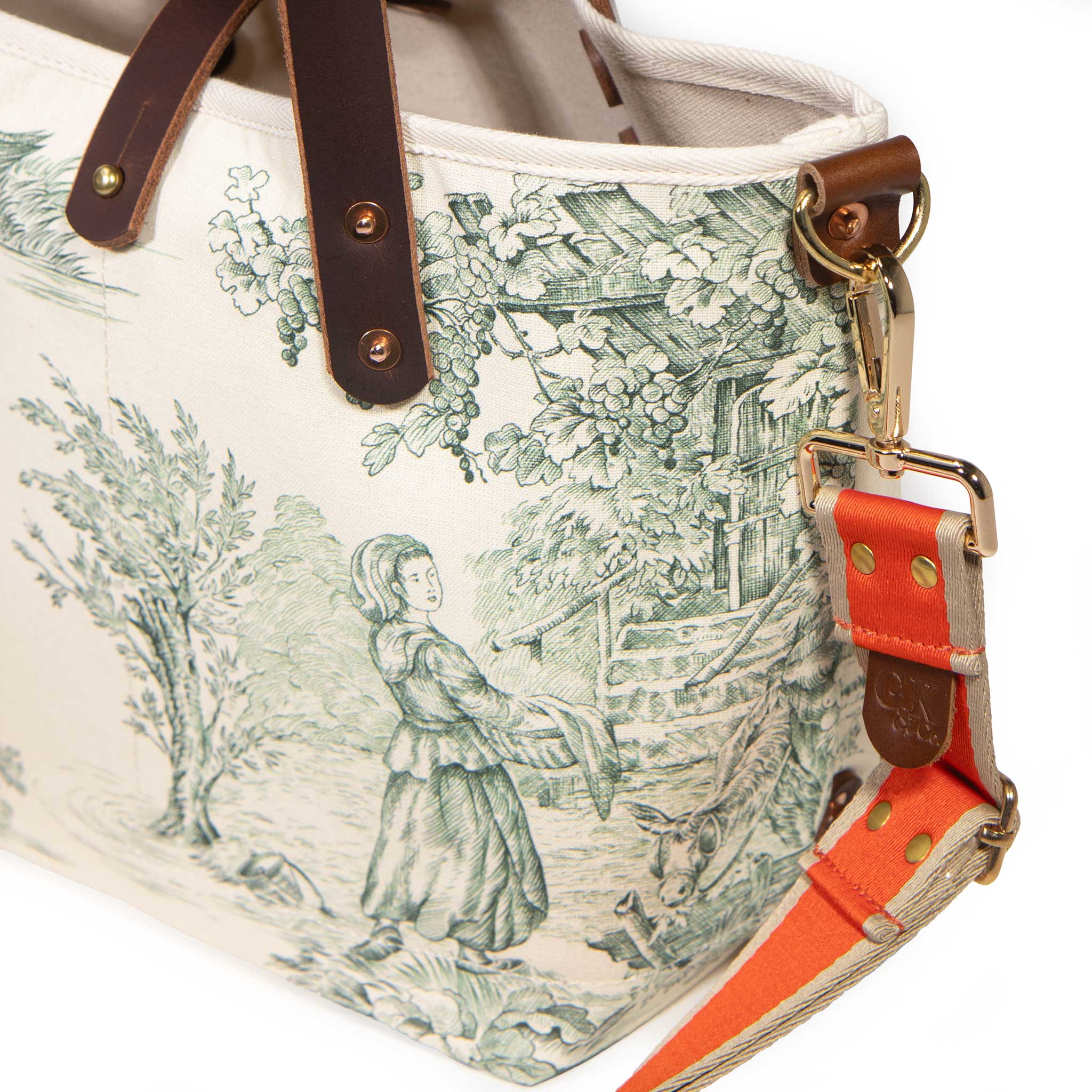 Close-up of the orange striped strap clipped to the brass D-ring of the Butter and Pine Toile Mini Tote