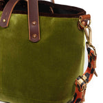 Close-up of the peridot green velvet, brown velvet binding and brass D-ring with the leopard strap clipped on