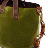 Close-up of the peridot green velvet, brown velvet binding and brass D-ring with the leopard strap clipped on