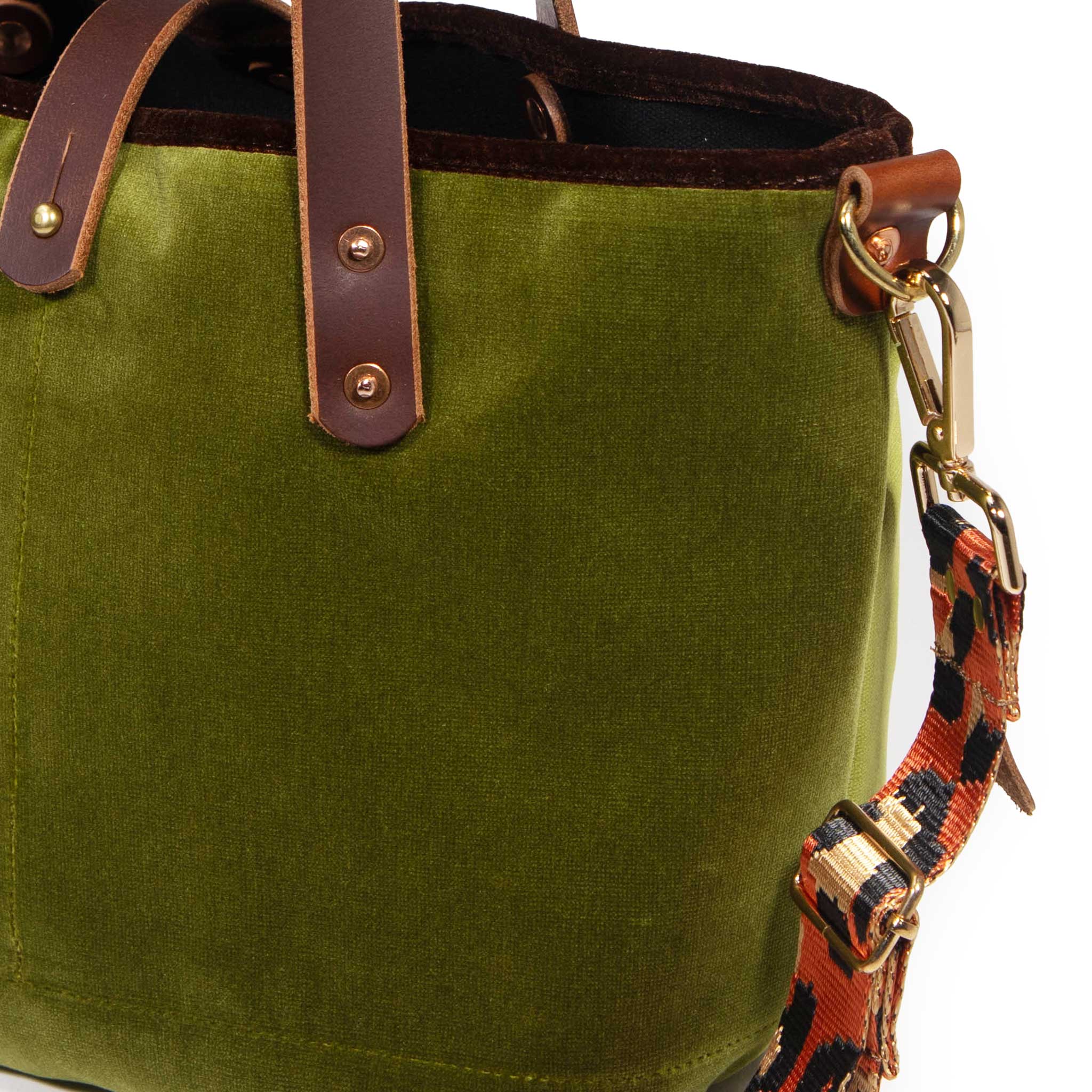 Close-up of the peridot green velvet, brown velvet binding and brass D-ring with the leopard strap clipped on