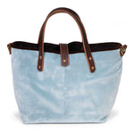 Front of the glacier blue Luxe Velvet Mini Tote, with mahogany leather handles, copper rivets and a button tab