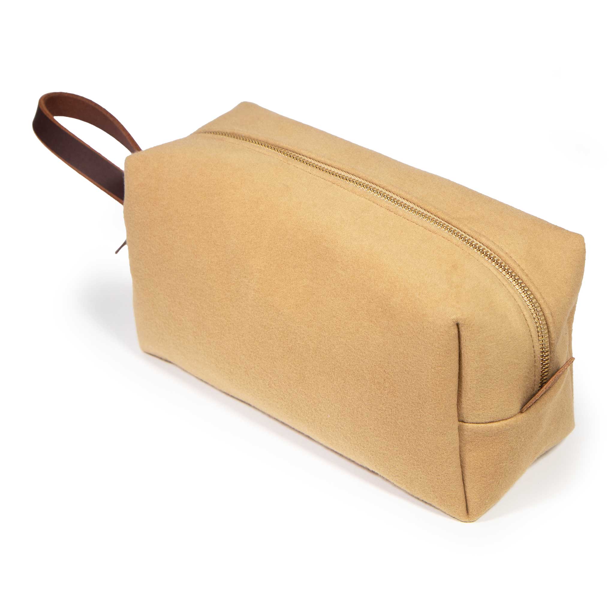 Camel Microsuede Travel Kit, three-quarter view: a velvety camel microsuede dopp kit with a brass YKK zipper and a mahogany leather loop handle