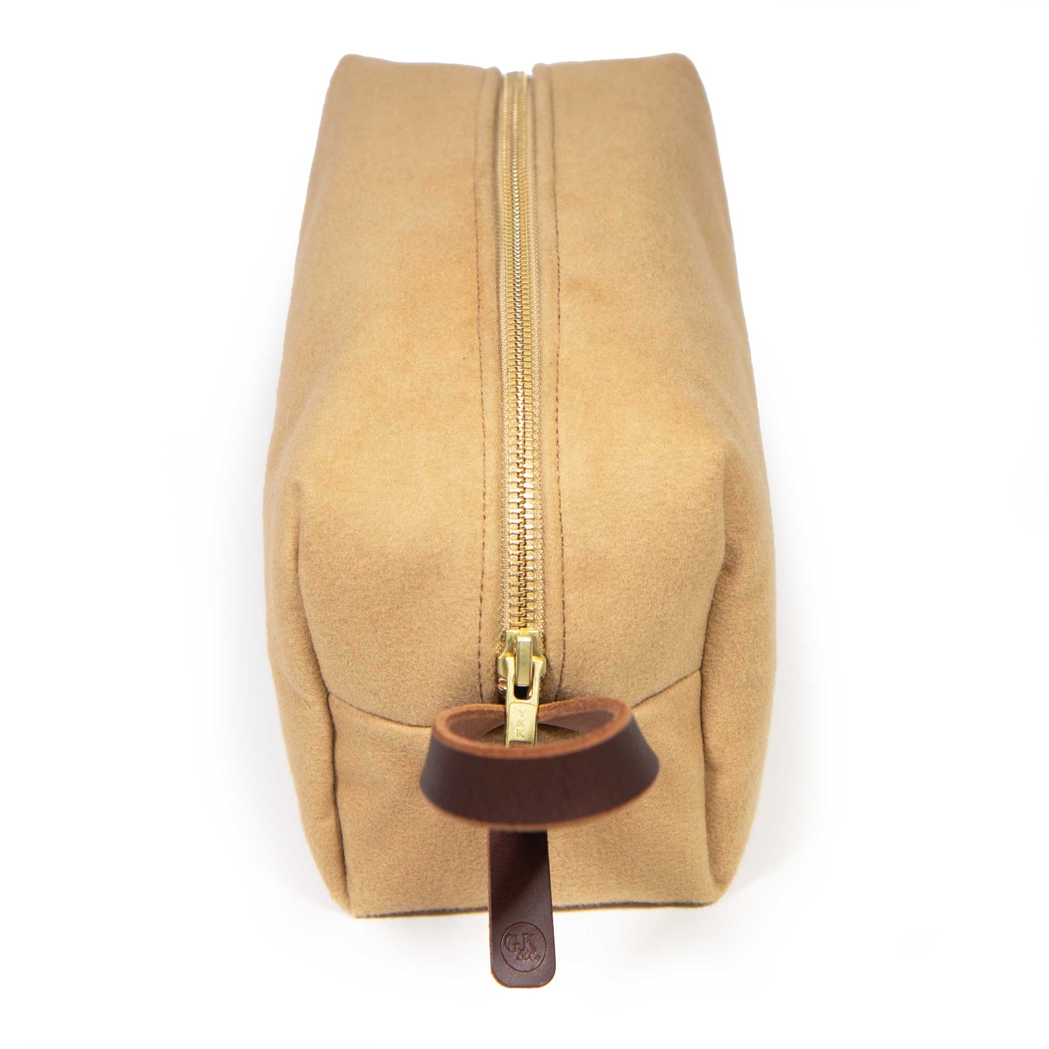 Top view of the Camel Microsuede Travel Kit: brass YKK zipper running the length, with a mahogany leather zipper pull stamped with the General Knot logo
