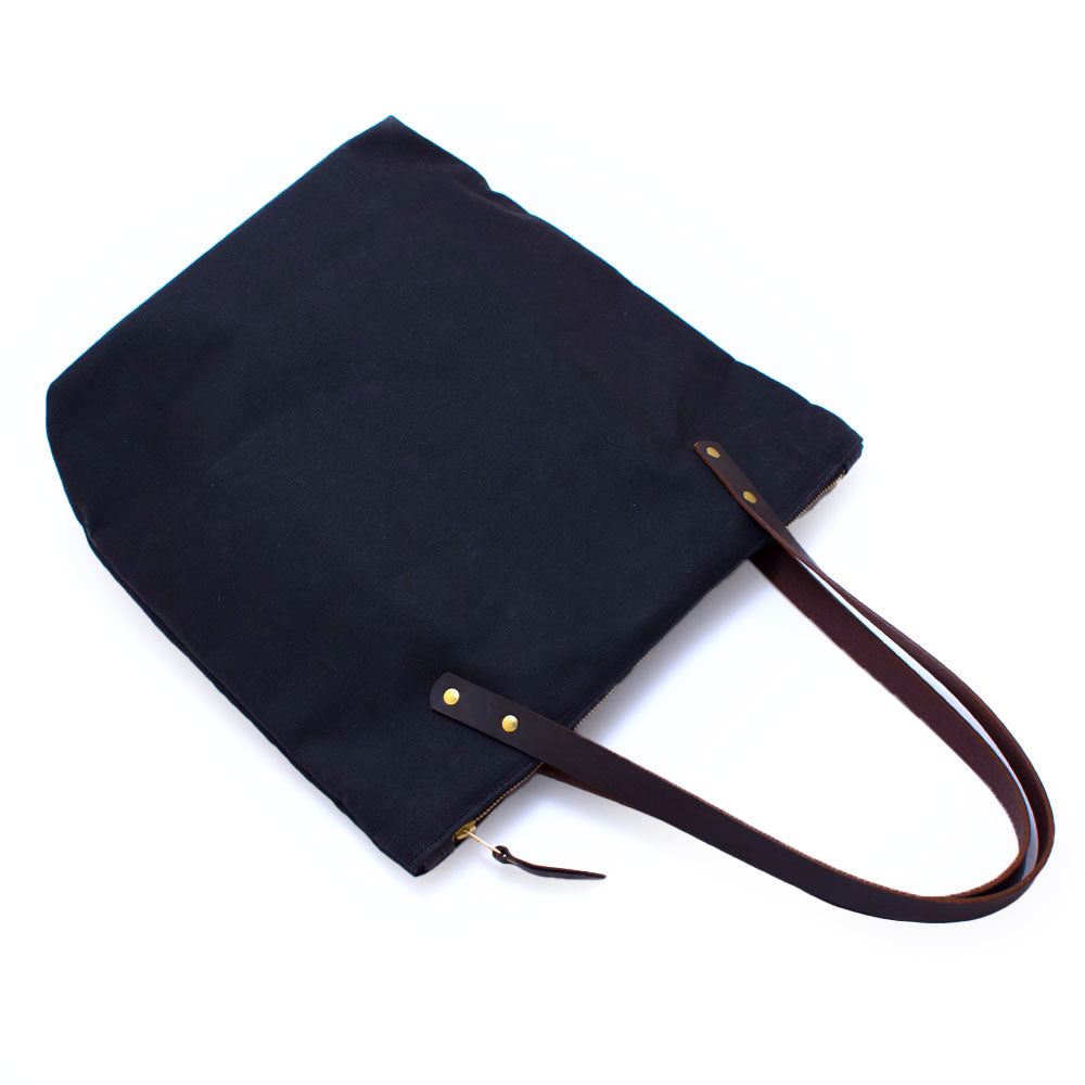Navy waxed canvas portfolio tote with brown leather handles and zipper