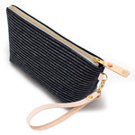 The Indigo Chalk Stripe Travel Clutch, white chalk stripes on indigo, shown with its detachable blonde leather wristlet clipped to a brass D-ring