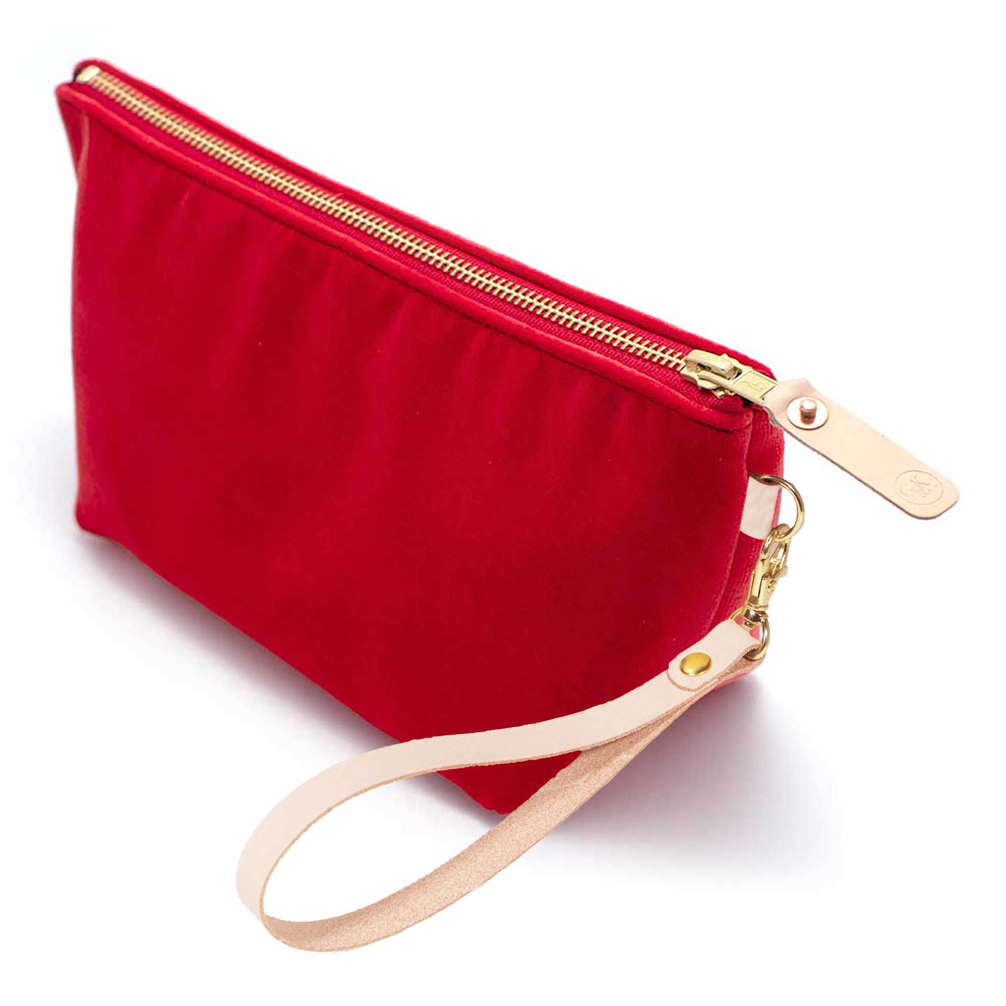 The Cherry Red Velvet Travel Clutch, cherry red velvet, shown with its detachable blonde leather wristlet clipped to a brass D-ring