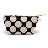Front of the Monster Dot Travel Clutch, oversized cream dots on black, with brass zipper and blonde leather pull