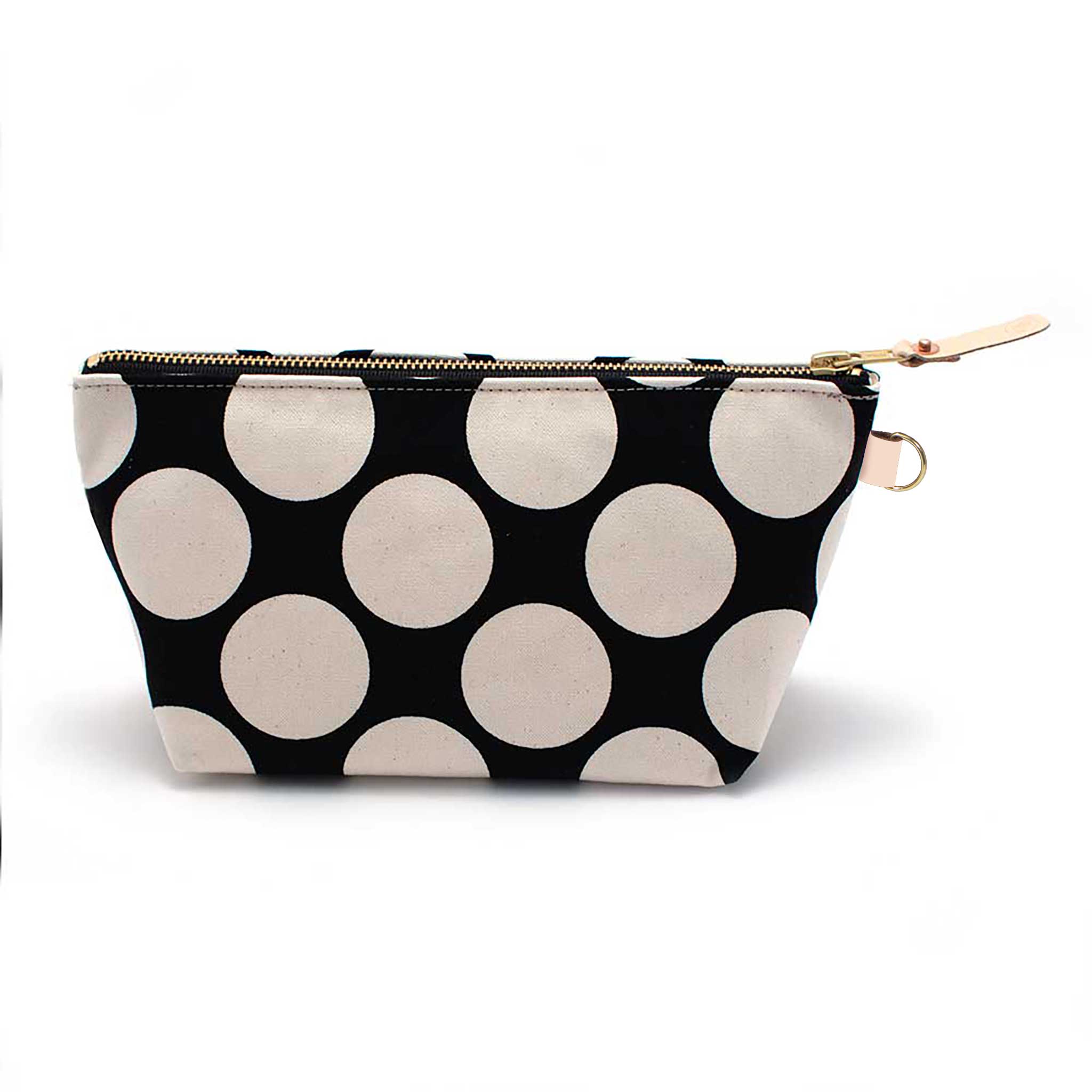Front of the Monster Dot Travel Clutch, oversized cream dots on black, with brass zipper and blonde leather pull