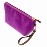 The Fuchsia Velvet Travel Clutch, fuchsia velvet, shown with its detachable mahogany leather wristlet clipped to a brass D-ring
