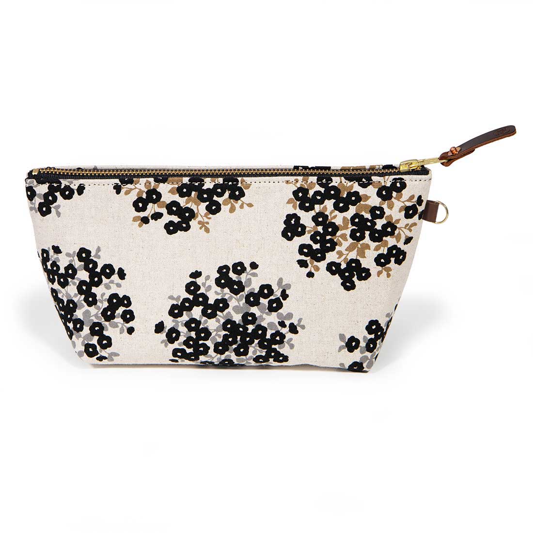 Front of the Dots & Blooms Travel Clutch, black dots and blooms on cream, with brass zipper and mahogany leather pull