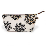 Front of the Dots & Blooms Travel Clutch, black dots and blooms on cream, with brass zipper and mahogany leather pull