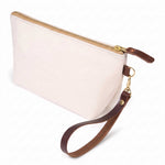 The Natural Canvas Travel Clutch, natural flecked canvas, shown with its detachable mahogany leather wristlet clipped to a brass D-ring
