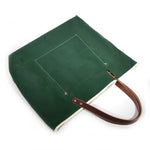 Dark green waxed canvas tote bag with contrast stitching and brown leather handles